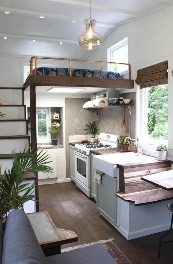 Compact ADU kitchen with an island and a sleeping loft reached by a ladder stair