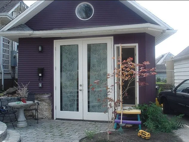Small single-storey granny suite cottage with french doors and a stone patio